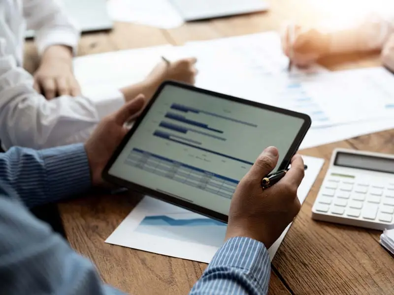 Over the shoulder view of a man using a tablet to review financials