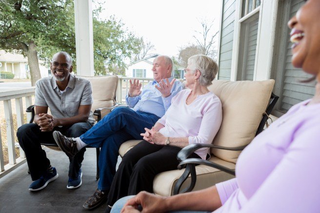 Older adults sitting on a porch talking and laughing