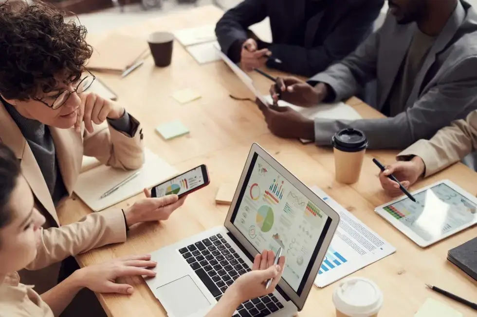 Group of people sitting around a conference table reviewing charts and financials